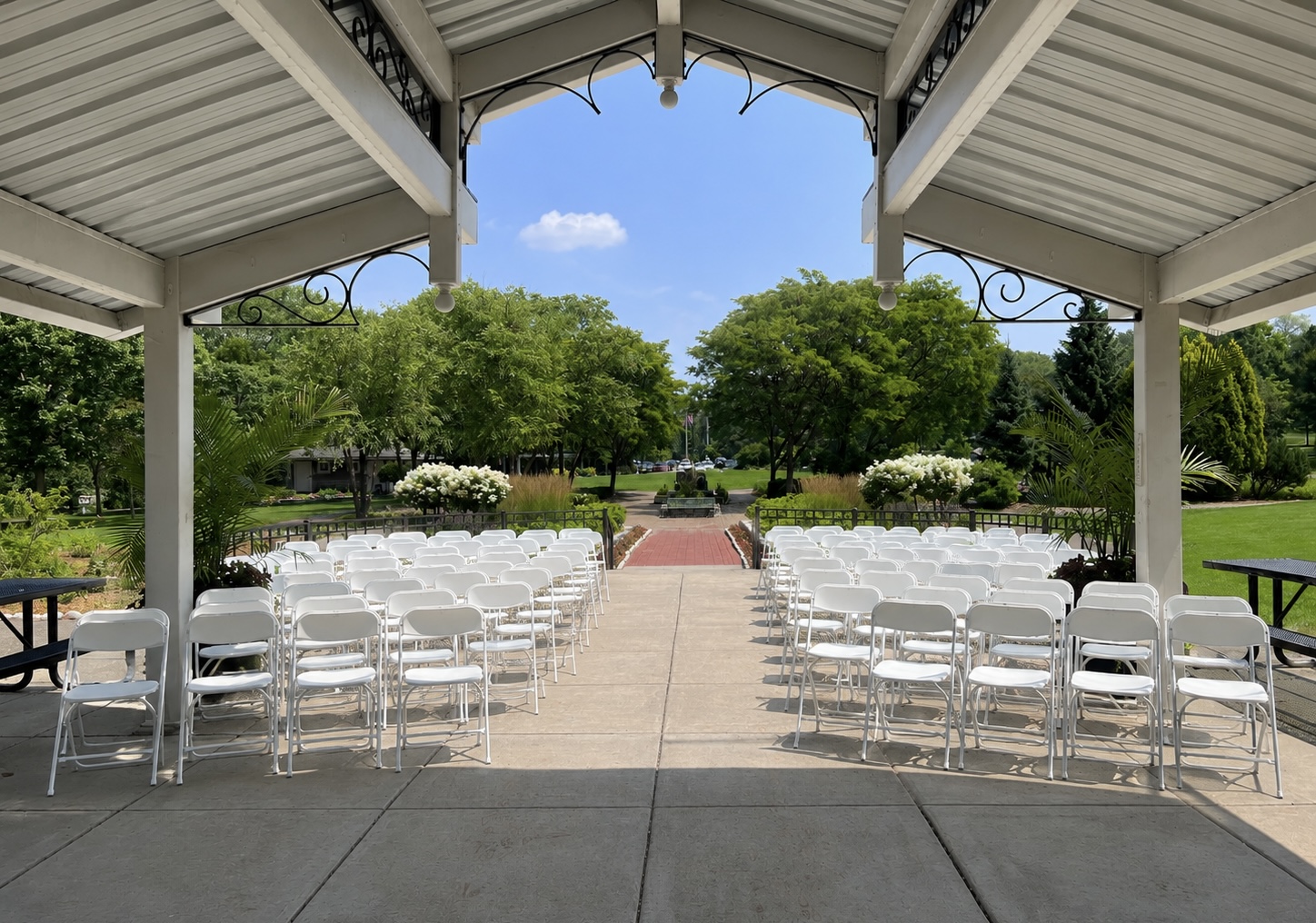 White folding chairs arranged under a pavilion for an elegant outdoor ceremony